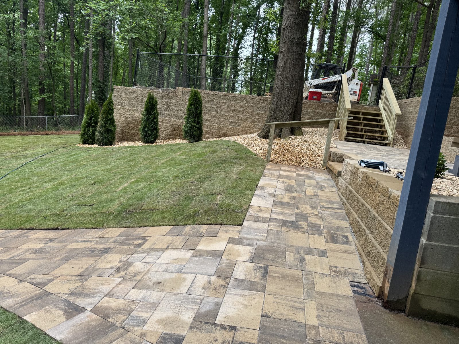 Paver walkway and fresh sod beside deck stairs